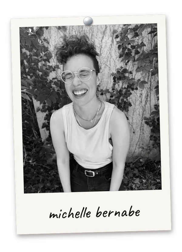 Black-and-white Polaroid photograph of co-host Michelle Bernabe laughing in front of an ivy-covered wall, pinned at the top with a handwritten caption reading michelle bernabe.